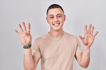 Canvas Print - Young man standing over isolated background showing and pointing up with fingers number nine while smiling confident and happy.