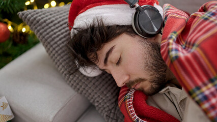 Wall Mural - Young hispanic man celebrating christmas sleeping on sofa at home