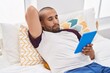 © Krakenimages.com - Young latin man using touchpad lying on bed at bedroom
