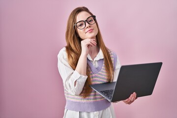 Wall Mural - Young caucasian woman working using computer laptop with hand on chin thinking about question, pensive expression. smiling and thoughtful face. doubt concept.