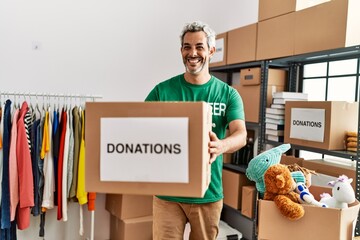 Sticker - Middle age grey-haired man volunteer smiling confident holding donations package at charity center