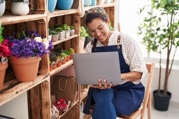 Wall Mural - Young beautiful hispanic woman florist smiling confident using laptop at florist