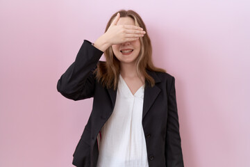 Wall Mural - Young caucasian business woman wearing black jacket smiling and laughing with hand on face covering eyes for surprise. blind concept.