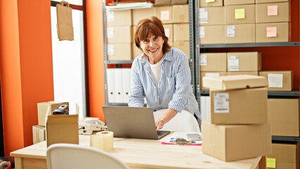 Poster - Middle age woman ecommerce business worker using laptop smiling at office