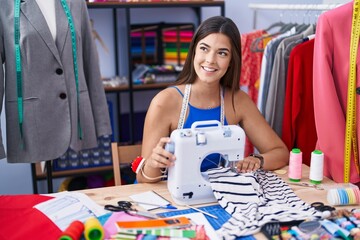 Canvas Print - Young beautiful hispanic woman tailor smiling confident using sewing machine at tailor shop