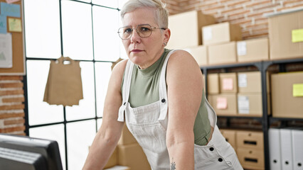 Sticker - Middle age grey-haired woman ecommerce business worker standing with serious face at office