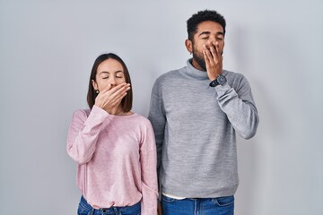 Wall Mural - Young hispanic couple standing together bored yawning tired covering mouth with hand. restless and sleepiness.