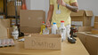 © Krakenimages.com - Young hispanic man volunteer putting products on donation cardboard box at charity center