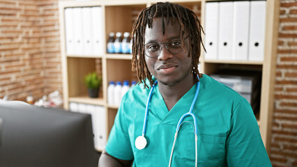 Wall Mural - African american man doctor using computer smiling at the clinic