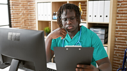 Wall Mural - African american man doctor using computer reading medical report at the clinic