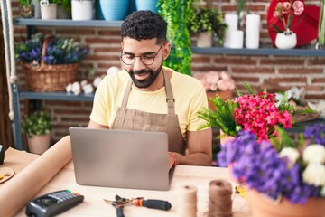 Sticker - Young arab man florist smiling confident using laptop at florist