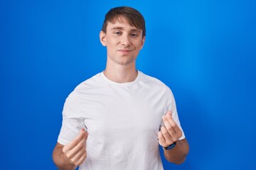 Poster - Caucasian blond man standing over blue background doing money gesture with hands, asking for salary payment, millionaire business