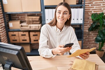 Poster - Young caucasian woman ecommerce business worker using smartphone holding package at office