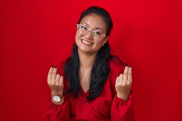 Poster - Asian young woman standing over red background doing money gesture with hands, asking for salary payment, millionaire business