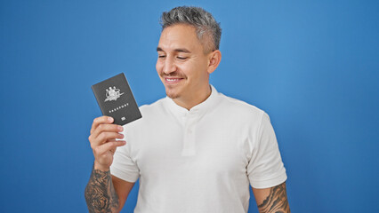 Sticker - Young hispanic man smiling confident holding passport over isolated blue background