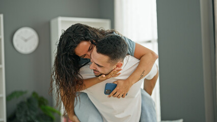 Poster - Man and woman couple holding smartphone holding girlfriend on back at home