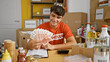 Smiling young hispanic teenager joyfully volunteers at charity center, confidently holding iceland krona banknotes
