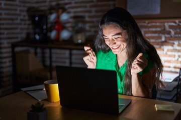 Sticker - Young teenager girl working at the office at night excited for success with arms raised and eyes closed celebrating victory smiling. winner concept.