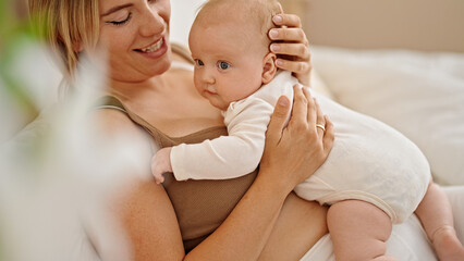 Wall Mural - Mother and daughter lying on bed hugging at bedroom