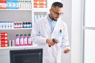 Poster - Young hispanic man pharmacist scanning pills bottle at pharmacy