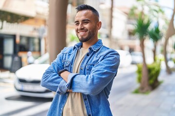 Canvas Print - Young hispanic man smiling confident standing with arms crossed gesture at street