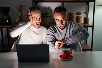 Canvas Print - Homosexual couple using computer laptop looking at the watch time worried, afraid of getting late