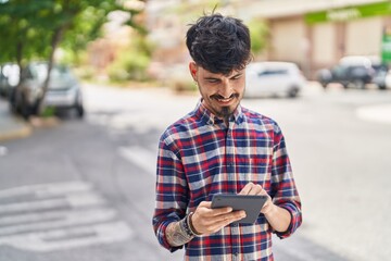 Sticker - Young hispanic man smiling confident using touchpad at street