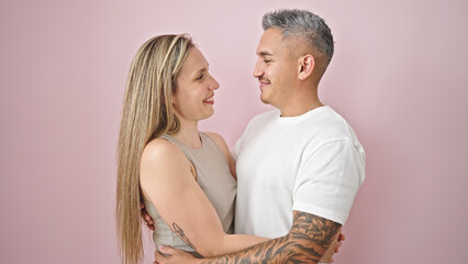 Wall Mural - Man and woman couple hugging each other smiling over isolated pink background