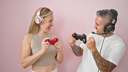 Sticker - Man and woman couple playing video game smiling over isolated pink background