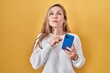 Young blonde woman using smartphone typing message thinking concentrated about doubt with finger on chin and looking up wondering
