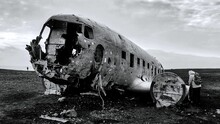 Grayscale shot of an old crashed plane in a field.