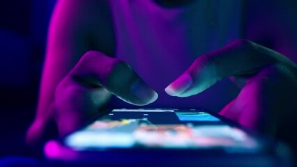 Finger of woman touching scroll page app on mobile phone.In a room with blue and purple neon tones.concept Social media and marketing