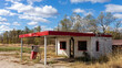 An abandoned derelict gas station with one broken pump