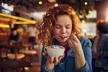 Young Woman Tasting Coffee With Spoon In Cafe
