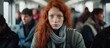 © AkuAku - In Germany a woman with fiery red hair is seated on a train in motion glancing directly at the camera