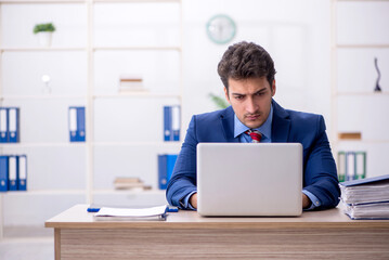 Wall Mural - Young male employee working in the office