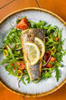 Healthy diner with sea bass fillet and vegetable salad, seabass fish. Orange background. Top view