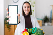 Young happy nutritionist woman showing mobile phone with white blank screen. Mockup template on smartphone device.