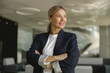© Yaroslav Astakhov - Portrait of smiling female entrepreneur with crossed hands standing in office and looks away