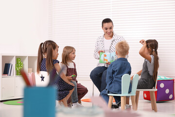 Wall Mural - Nursery teacher and group of cute little children learning animals in kindergarten. Playtime activities