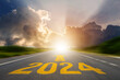 New year 2024 or straight forward concept. Text 2024 was written on the road in the middle of the asphalt road at sunset. Concept of planning, goal, challenge, new year resolution.