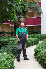 Wall Mural - A blond man in work clothes in the green courtyard large house.