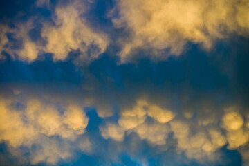 sunlit bizarre clouds in dark blue sky