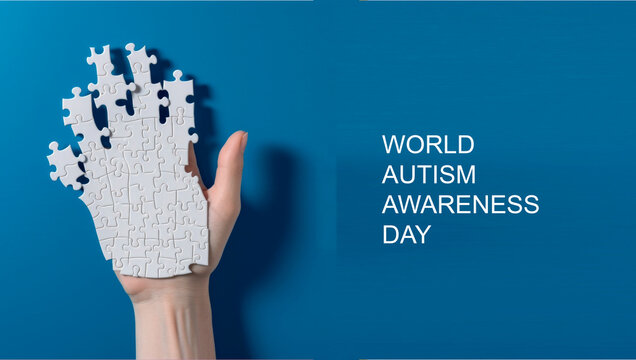 World autism awareness day banner.A human hand made from a white puzzles . The concept of personality development and treatment
