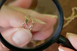 jeweler looking at golden chain through magnifying glass, jewerly inspect and verify, pawnshop