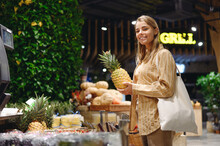 Young Customer Woman Wears Casual Clothes Holding Pine-apple Shopping With Shopper Bag At Supermaket Store Grocery Shop Buying Fruit Choose Products In Hypermarket. Purchasing Food Gastronomy Concept.