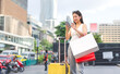 © dodotone - Asian woman using smartphone with luggage people city lifestyles travel with shopping