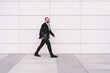 © BullRun - Serious businessman walking on street with folder