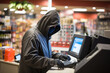 masked criminal robs a cash register in a store.