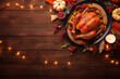 Top view Thanksgiving banner with roast turkey dish on rustic table with candles and string lights. Promotional materials for holiday meal